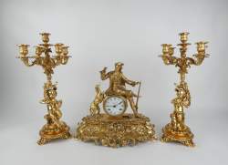 Horloge : Garniture de cheminée en laiton - chasseur et son chien - mouvement rond cachet KIENZLE et ses 2 chandeliers aux amours (1 branche leg pliée)